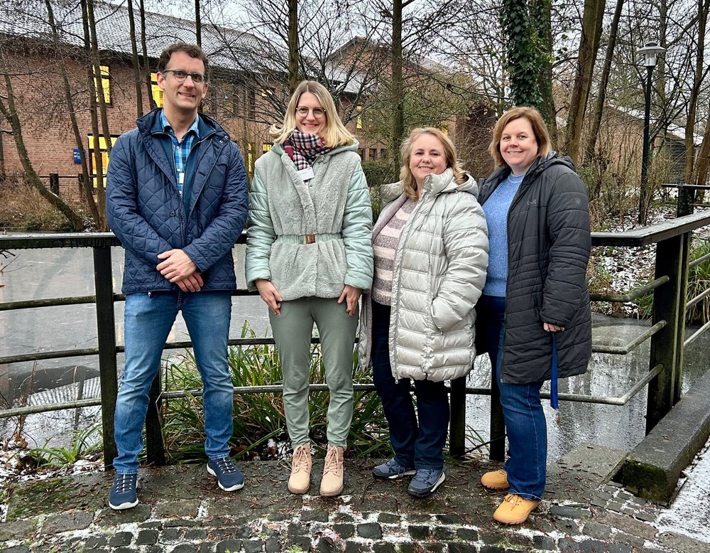 Vier Personen stehen gemeinsam im Freien an einem Geländer.