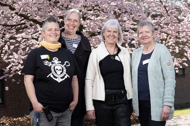 Vier Frauen stehen in einer Reihe und lächeln Vier Frauen stehen in einer Reihe und lächeln