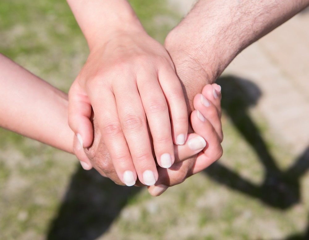 Drei Hände sternförmig übereinander gelegt