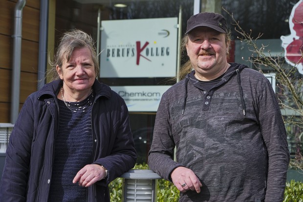 Die beiden Genesungsbegleiter:innen stehen vor der Schule, Hildegard Kofoth links und Guido Elfers rechts.