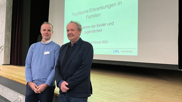 Zwei Männer stehen vor einer Leinwand auf der eine Präsentation gezeigt wird. Zwei Männer stehen vor einer Leinwand auf der eine Präsentation gezeigt wird.