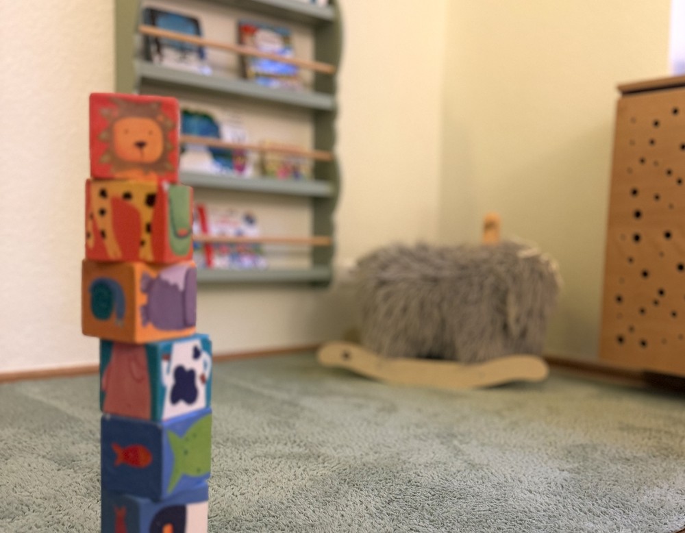 Gestapelter Turm aus bunten Holzklötzen in einem Spielraum