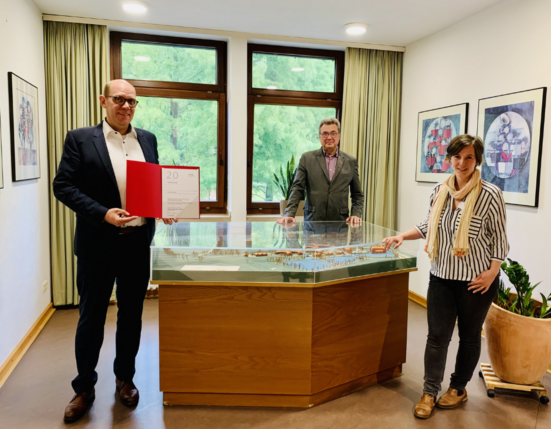 Stephan Köchling zeigt das DGQ-Zertifikat im Beisein von Heinz Augustin und Anne Sophie Scholz.