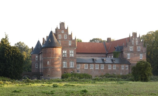 Das Schloss der LWL-Klinik Herten von der Rückseite betrachtet, umgeben von Wiese und Bäumen rechts und links im Bild. Bildquelle: LWL