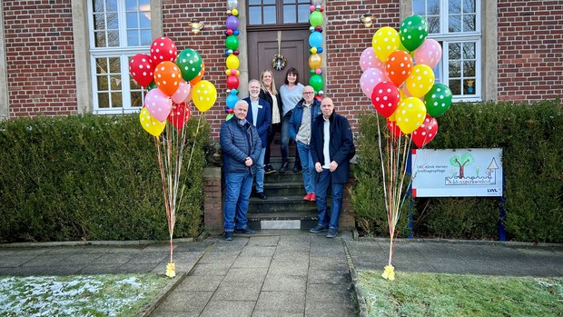 Mitarbeitende vor dem Eingang der Großtagespflege Schlossparkwichtel, geschmückt mit bunten Luftballons.
