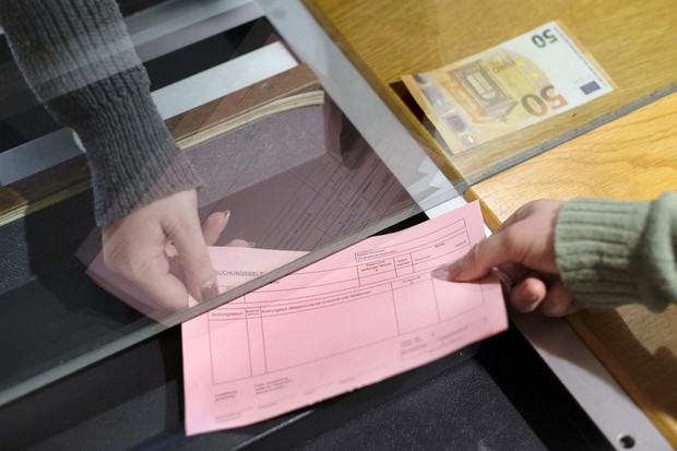 Die Hand einer Frau hält einen Buchungsbeleg an der Kasse zwecks Übergabe, 50 Euro-Schein liegt bereit Die Hand einer Frau hält einen Buchungsbeleg an der Kasse zwecks Übergabe, 50 Euro-Schein liegt bereit