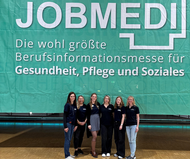 Sechs Personen stehen vor einem großen JOBMEDI-Banner auf einer Berufsinformationsmesse.