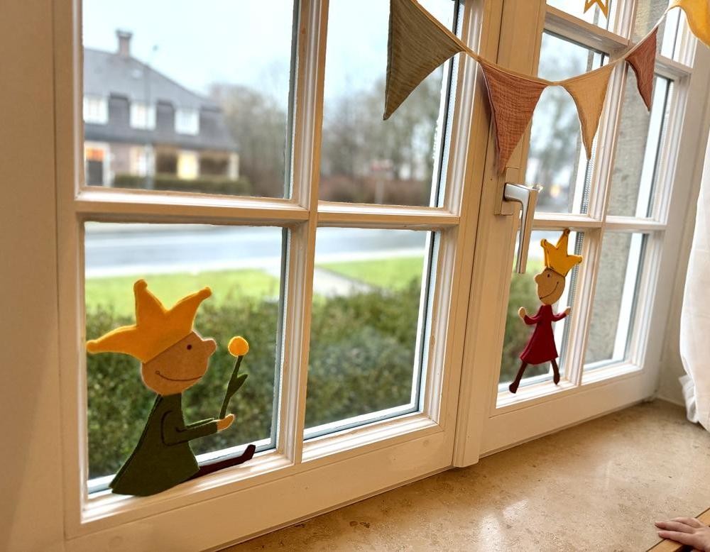 Fenster mit Stofffiguren und Wimpelkette, Blick nach draußen auf Straße und Haus