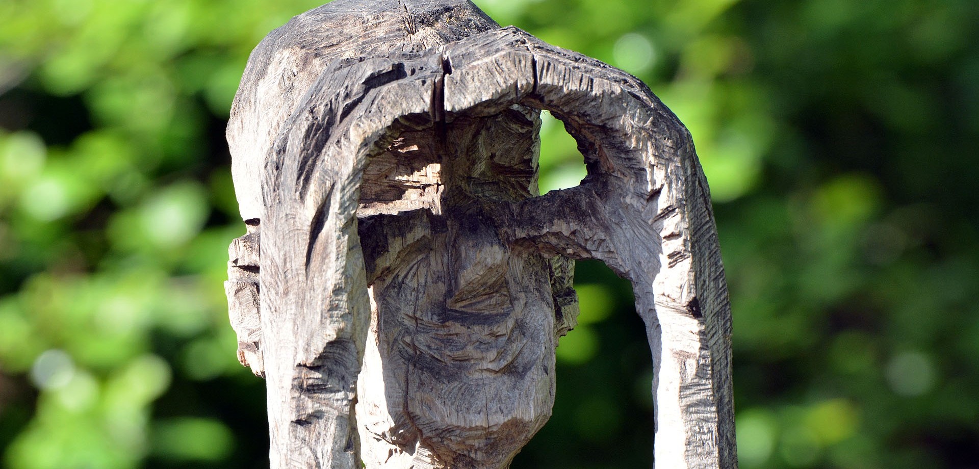 Eine Holzfigur-Skulptur in einem der Klinikteiche schirmt mit seinen Händen die Augen ab und schaut in eine Richtung. Bildquelle: LWL/Bourichter
